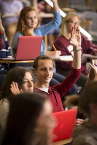 Students in a class raising their hands to answer a question